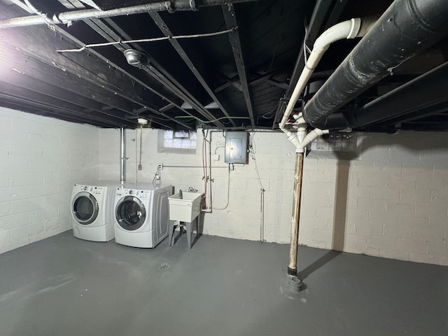 basement with a sink, washing machine and clothes dryer, and electric panel