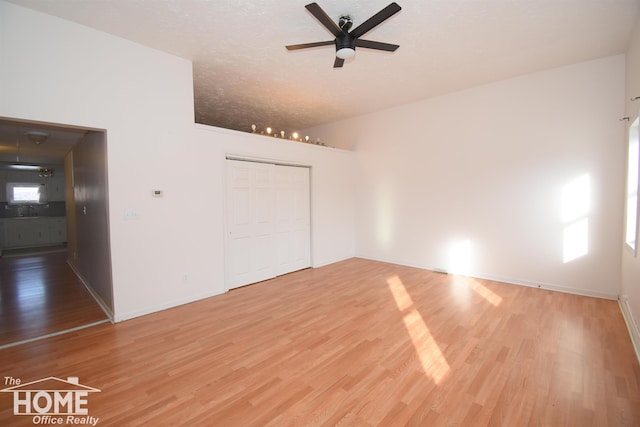 unfurnished bedroom featuring a closet, a sink, a textured ceiling, light wood-type flooring, and baseboards