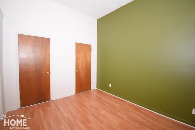 unfurnished bedroom featuring a textured ceiling, high vaulted ceiling, and light wood finished floors