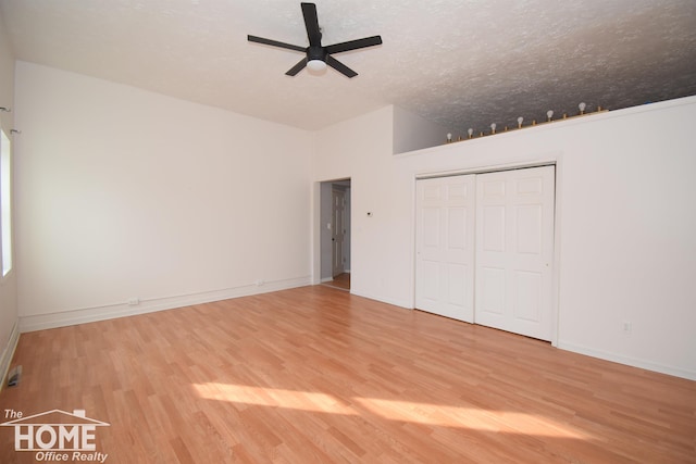 unfurnished bedroom featuring a closet, a textured ceiling, baseboards, and wood finished floors