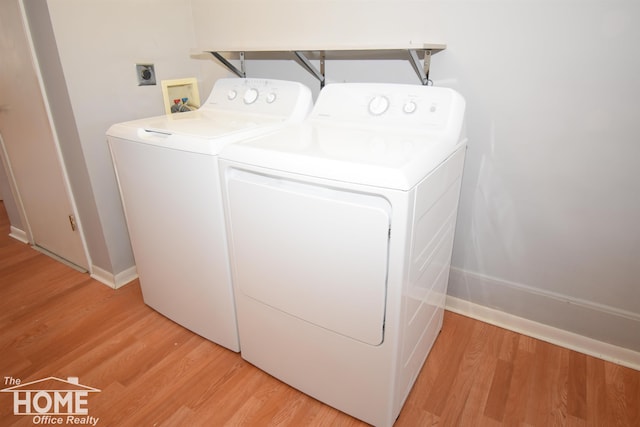 laundry room featuring baseboards, washing machine and dryer, and light wood-style floors