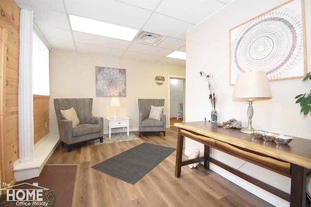 sitting room with a paneled ceiling, visible vents, and wood finished floors