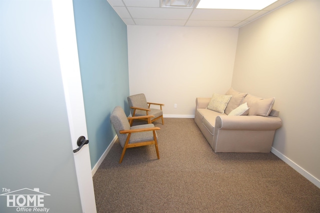 sitting room featuring carpet floors, a drop ceiling, and baseboards