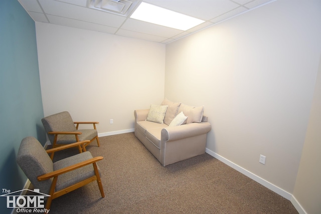 living area featuring carpet floors, baseboards, and a drop ceiling