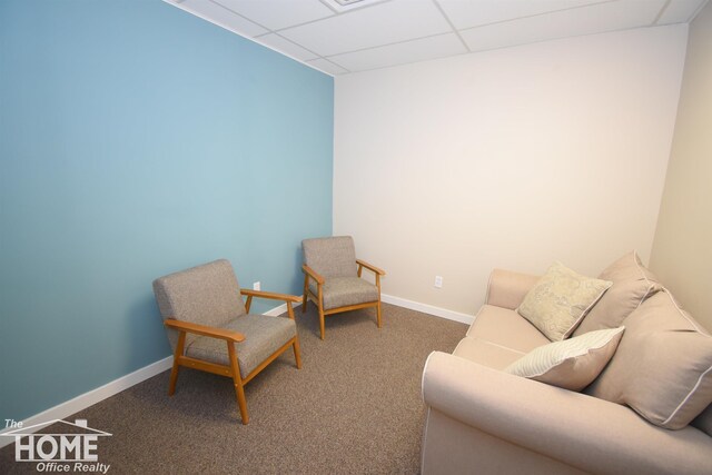 living area with carpet floors, baseboards, and a drop ceiling