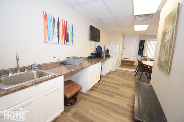 kitchen with visible vents, white cabinets, a drop ceiling, light wood-style flooring, and a sink