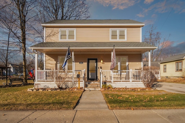 view of front facade with a porch, a front yard, and roof with shingles