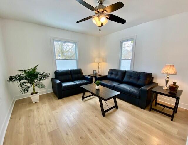 living area featuring plenty of natural light, light wood-style flooring, and baseboards