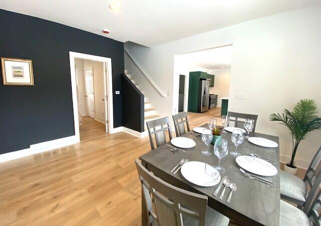 dining room featuring light wood finished floors, stairway, and baseboards