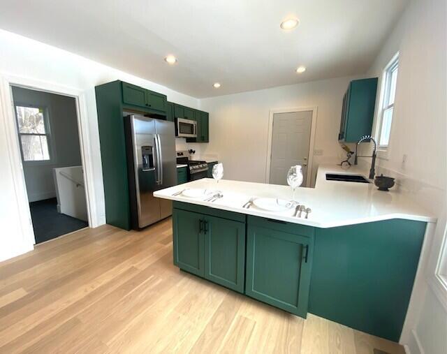 kitchen featuring appliances with stainless steel finishes, light countertops, and green cabinetry