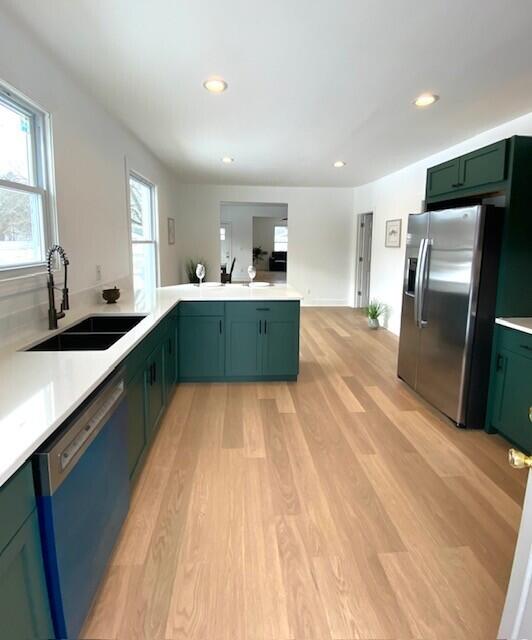 kitchen featuring green cabinetry, dishwasher, stainless steel fridge with ice dispenser, light wood-style flooring, and a sink