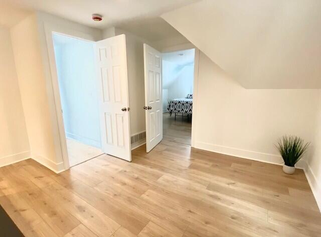 bonus room featuring baseboards, vaulted ceiling, and light wood finished floors