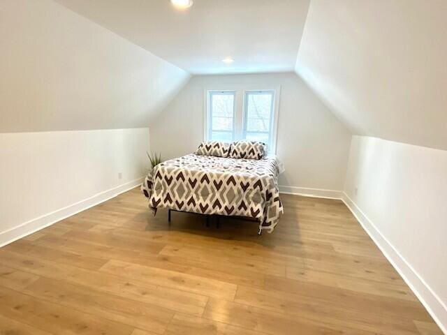 bedroom with lofted ceiling, light wood-style floors, baseboards, and recessed lighting