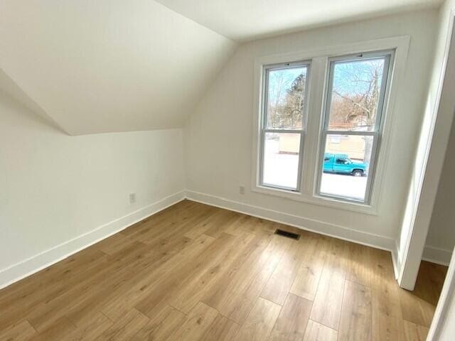 bonus room featuring vaulted ceiling, light wood-style flooring, and baseboards