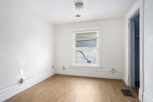 spare room featuring hardwood / wood-style flooring, baseboards, and visible vents