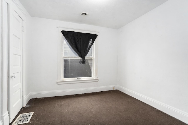 spare room with baseboards, visible vents, and dark colored carpet