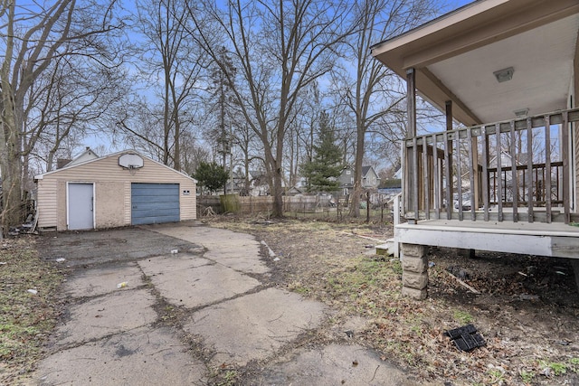 view of yard featuring a detached garage, fence, concrete driveway, and an outbuilding