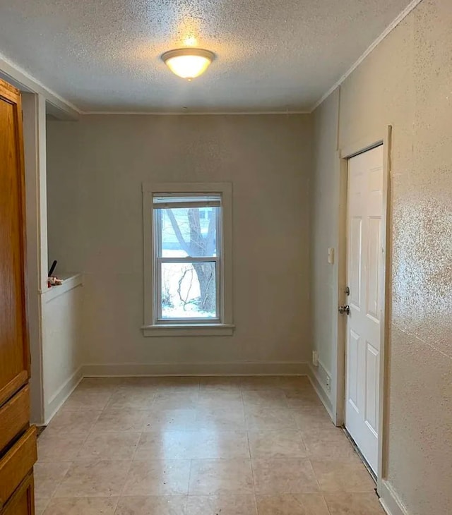 empty room with a textured wall, baseboards, and a textured ceiling