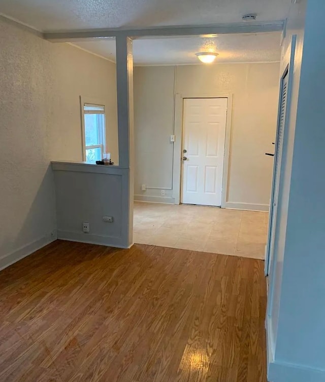 unfurnished room with baseboards, a textured wall, and wood finished floors