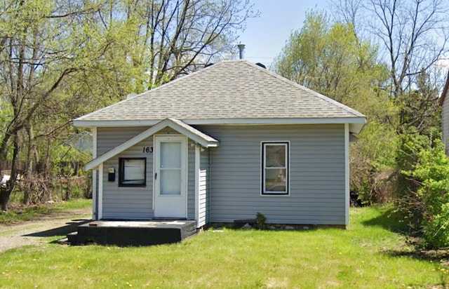 view of front facade with a shingled roof and a front lawn