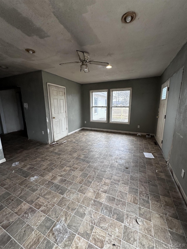 unfurnished room featuring ceiling fan, a textured ceiling, and baseboards