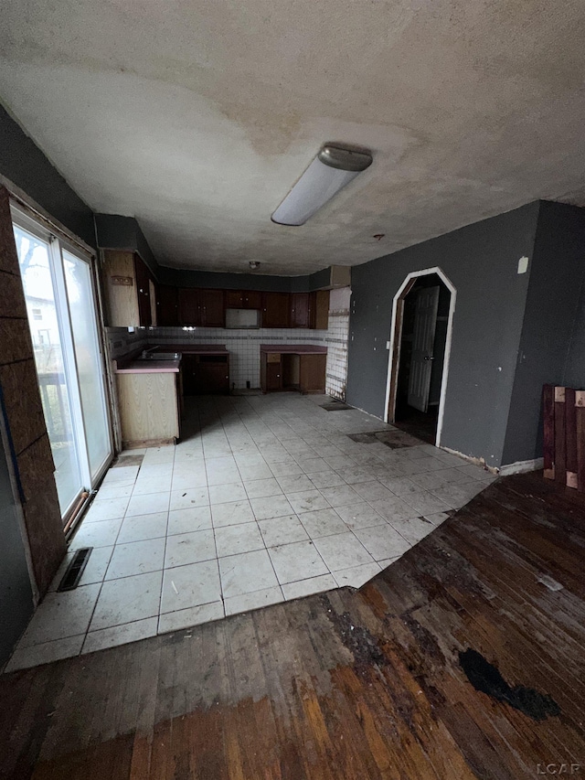 kitchen featuring light wood finished floors, visible vents, arched walkways, open floor plan, and a textured ceiling