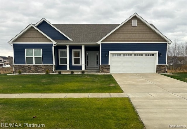 craftsman-style house featuring an attached garage, covered porch, stone siding, driveway, and a front lawn