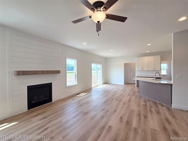 13059 River Rock Pass, Linden, MI 48451 - unfurnished living room with recessed lighting, light wood-style floors, a large fireplace, baseboards, and a sink