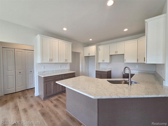 13059 River Rock Pass, Linden, MI 48451 - kitchen with a peninsula, light stone counters, white cabinets, recessed lighting, and light wood-type flooring