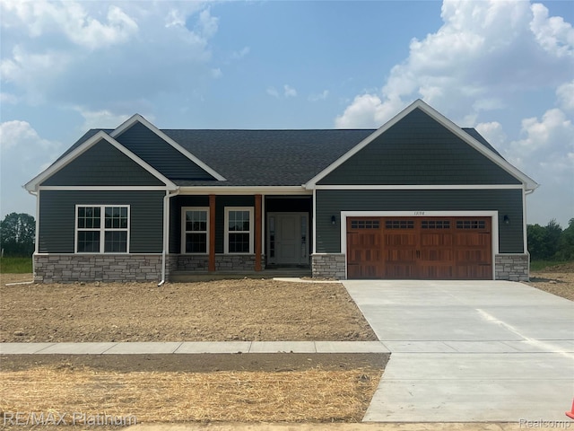 13059 River Rock Pass, Linden, MI 48451 - craftsman-style house featuring stone siding, an attached garage, driveway, and covered porch
