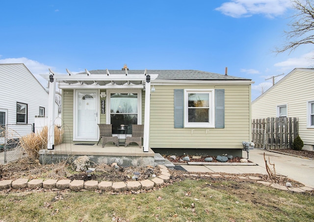 rear view of house with covered porch and fence