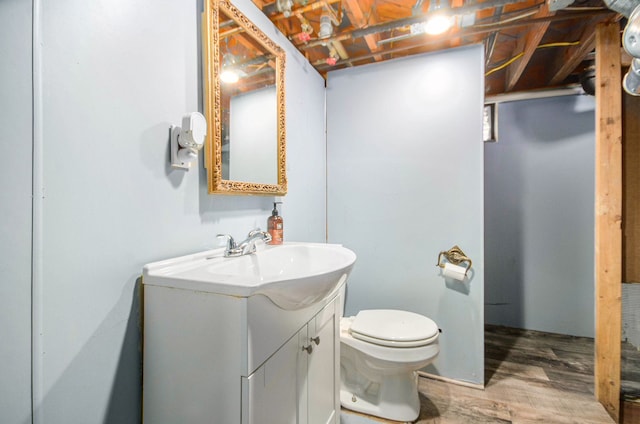 half bath featuring vanity, toilet, and wood finished floors