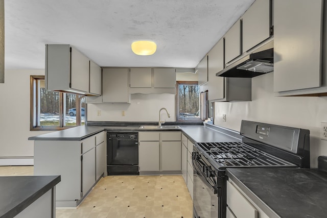 kitchen featuring dark countertops, under cabinet range hood, a peninsula, black appliances, and a sink