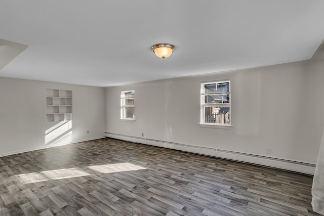 spare room with wood finished floors, baseboards, and baseboard heating