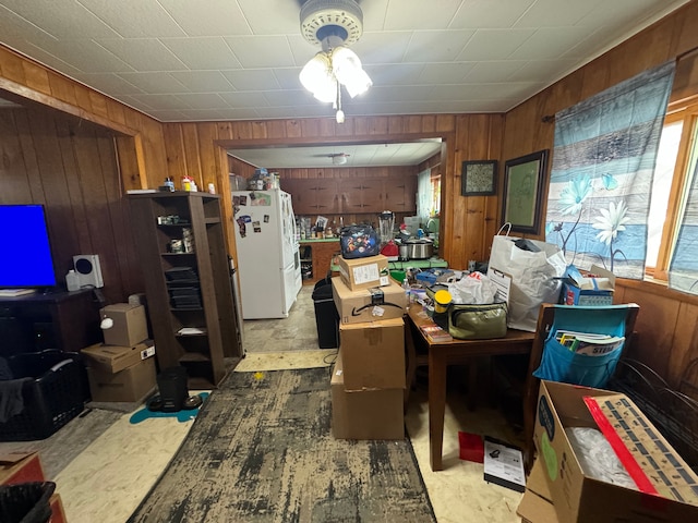 interior space featuring wood walls and freestanding refrigerator