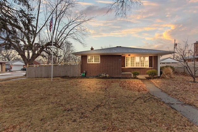 exterior space featuring brick siding, a chimney, a front yard, and fence