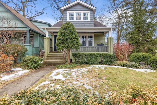 view of front facade with covered porch, a shingled roof, and a front yard