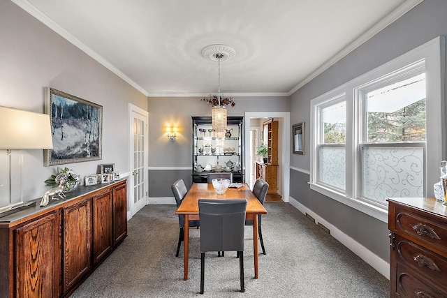 dining space featuring ornamental molding, dark colored carpet, and baseboards