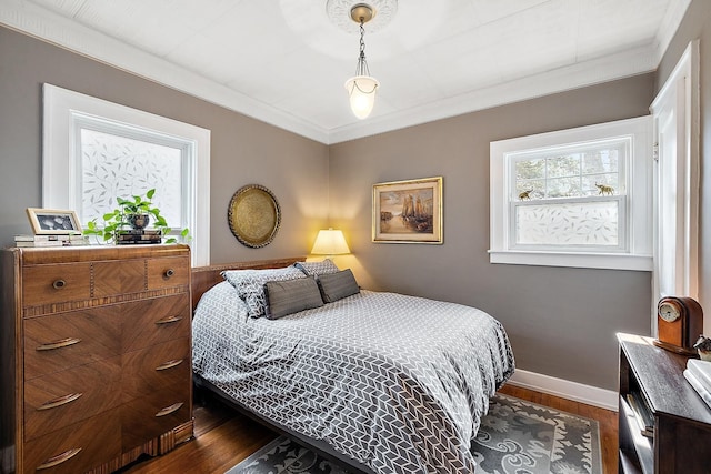 bedroom with baseboards, dark wood-type flooring, and crown molding