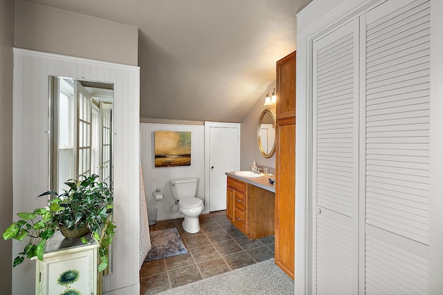 bathroom with lofted ceiling, a closet, vanity, and toilet