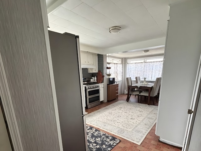 kitchen featuring appliances with stainless steel finishes, brick floor, and decorative backsplash