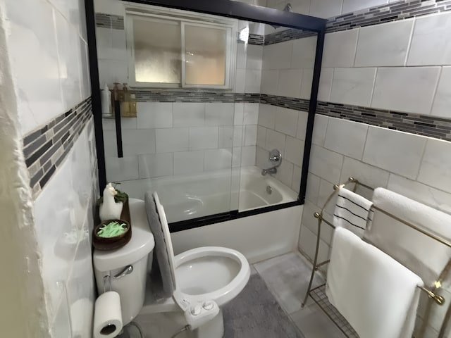 full bath featuring toilet, combined bath / shower with glass door, and tile walls