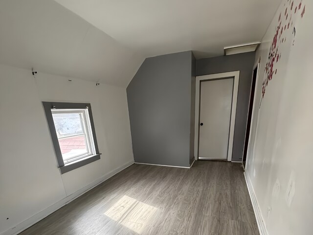 bonus room with baseboards, vaulted ceiling, and wood finished floors