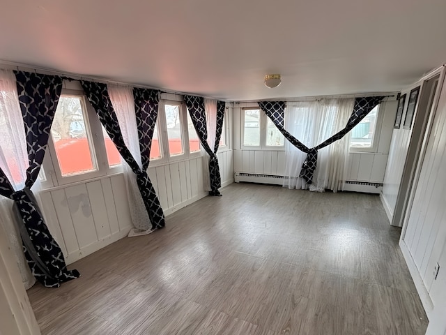 empty room featuring a baseboard radiator, baseboard heating, and wood finished floors