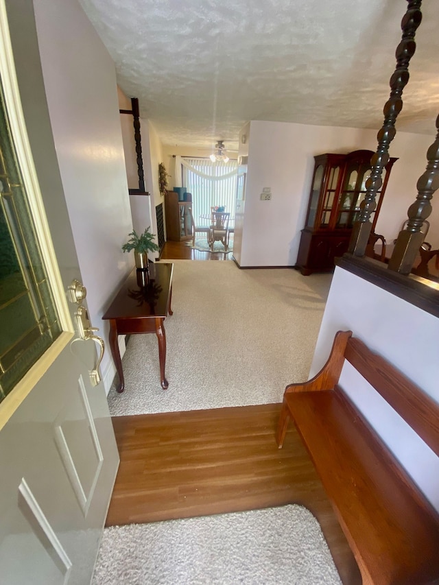 hall with carpet flooring, a textured ceiling, and wood finished floors