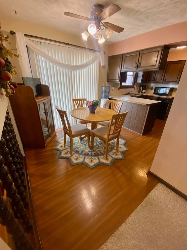 dining area with a ceiling fan, a textured ceiling, and wood finished floors