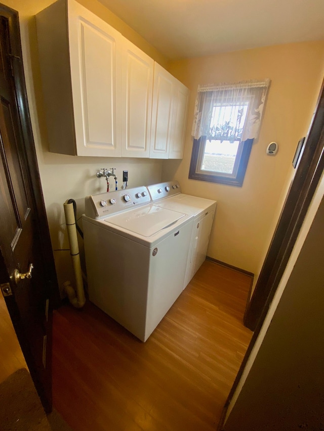 washroom with wood finished floors, cabinet space, and separate washer and dryer