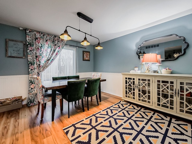 dining area with visible vents, wainscoting, radiator, and wood finished floors