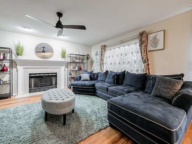 living room with a fireplace, wood finished floors, and a ceiling fan