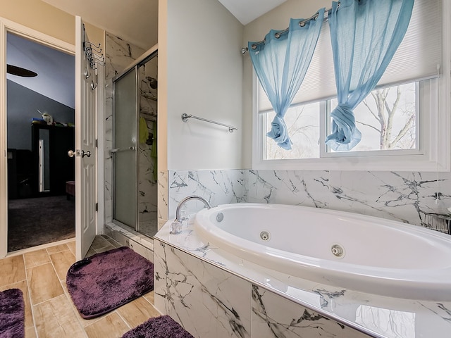 bathroom with wood finish floors, a tub with jets, and a stall shower